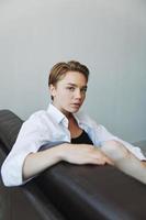 Women lying at home on the couch portrait with a short haircut in a white shirt, smile, depression in teenagers, home holiday photo