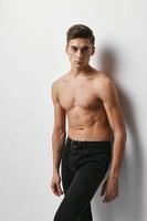 Handsome guy nude torso black pants light background model photo