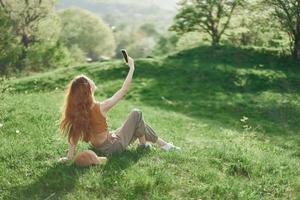 Top view of a woman with phone in hand freelance student trying to find internet connection in nature in a green summer park photo
