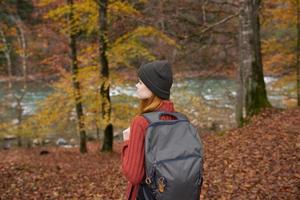 traveler with a backpack and in a gray hat in the autumn forest fallen leaves trees river model photo