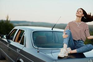 Woman sitting in her car on a road trip and relaxing, lifestyle on the road photo