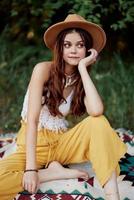 hermosa joven niña de cerca mira dentro el cámara en un sombrero vistiendo un eco hippie al aire libre, hermosa sonrisa con dientes en el puesta de sol ligero foto