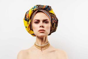 pretty woman holding her head decoration multicolored turban fashion light background photo