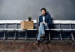 A man with things in a box sits on a chair waiting for discontent photo