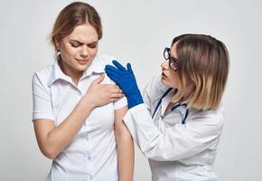 Female doctor in a medical gown and blue gloves examines a patient in a cropped view photo