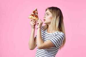 mujer en a rayas camiseta con Pizza en manos rápido comida bocadillo rosado antecedentes foto