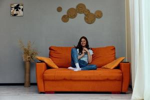 cheerful woman with a phone in his hands on the couch apartments photo