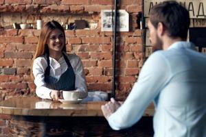 woman waiter brings coffee to a cafe client photo