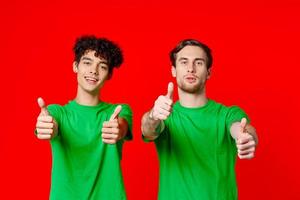 alegre amigos en verde camisetas gesticulando con manos emociones rojo antecedentes foto