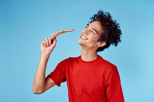 happy guy with slice of pizza on blue background curly hair emotions cropped view photo