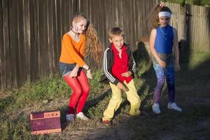 Retro kids. Two girls mi boy dressed in the style of the nineties are dancing to a retro tape recorder. photo