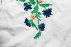 A piece of white cotton fabric with embroidered bright flowers. photo