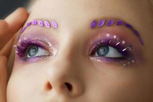 Female eyes with purple make-up. Beautiful extended eyelashes and eyebrows. photo