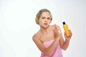 woman with unhappy facial expression in pink towel lotion skin care photo