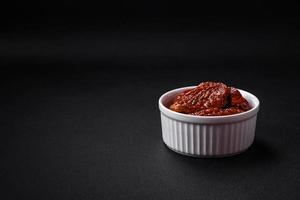 Delicious sun dried tomatoes in oil in a white ceramic bowl photo