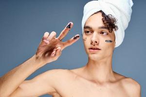 hermoso chico con un toalla en su cabeza desnudo espalda productos cosméticos limpiar piel foto