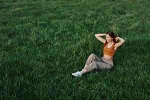 Young woman playing games in the park on the green grass spreading her arms and legs in different directions falling and smiling in the sunlight of summer, a lifestyle of life and youth photo