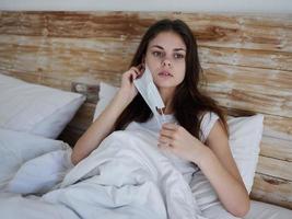 mujer mentiras en cama vistiendo un máscara médico descanso tratamiento foto