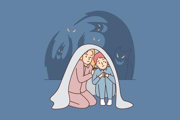 Teenage boy and girl sit wrapped in blanket scared of ghosts after watching scary movie or telling horror stories. Two children are afraid of dark and ghosts and need support of their parents