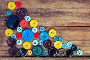 Lots of colorful buttons for clothes on wooden background. photo