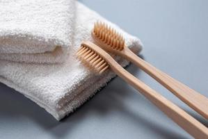 dos de madera cepillos de dientes y blanco toallas en gris antecedentes foto