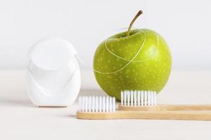 bambú cepillos de dientes, verde manzana y dental seda floja en blanco antecedentes - dental cuidado rutina a mantener sano dientes foto