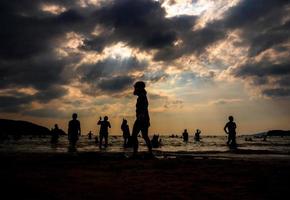 Silhouettes of people playing in the sea at a public beach photo