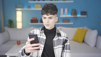 recepción malo noticias, el joven hombre es frustrado. joven hombre utilizando teléfono inteligente a hogar recibe malo Noticias temas video