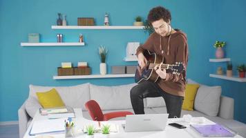 Young man immersed in the rhythm of the guitar. Young man playing guitar alone at home, immersing himself in the guitar. video