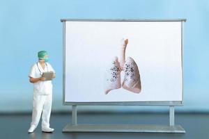 Miniature people. A doctor examines pneumonia in the picture, a respiratory disease. photo