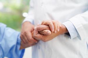 médico tomados de la mano paciente anciana asiática, ayuda y atención en el hospital. foto