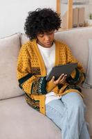 African american girl holding digital tablet touch screen typing scroll page at home. Woman with mobile tech device surfing internet using social media apps playing game. Study work shopping online. photo