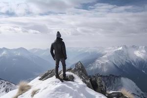 Man standing on the top of a snowcapped mountain peak. Panoramic view photo