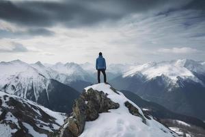 Man standing on the top of a snowcapped mountain peak. Panoramic view photo