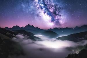 Milky Way over mountains in fog at night in summer. Landscape with foggy alpine mountain valley photo