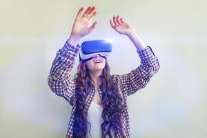 Smile young woman wearing using virtual reality VR glasses helmet headset on white background. Smartphone using with virtual reality goggles. Technology, simulation, hi-tech, videogame concept. photo