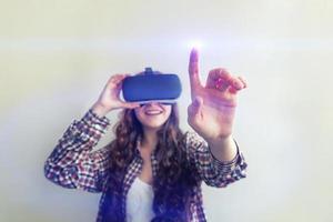 Smile young woman wearing using virtual reality VR glasses helmet headset on white background. Smartphone using with virtual reality goggles. Technology, simulation, hi-tech, videogame concept. photo