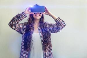 Smile young woman wearing using virtual reality VR glasses helmet headset on white background. Smartphone using with virtual reality goggles. Technology, simulation, hi-tech, videogame concept. photo