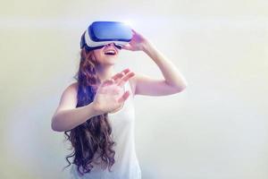sonrisa joven mujer vistiendo utilizando virtual realidad vr lentes casco auriculares en blanco antecedentes. teléfono inteligente utilizando con virtual realidad gafas de protección. tecnología, simulación, de alta tecnología, videojuego concepto. foto