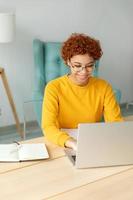 africano americano niña utilizando ordenador portátil a hogar oficina mirando a pantalla mecanografía chateando leyendo escritura correo electrónico. joven mujer teniendo virtual reunión en línea charla vídeo llamada conferencia trabajo aprendizaje desde hogar foto