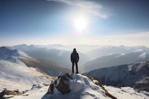 Man standing on the top of a snowcapped mountain peak. Panoramic view photo
