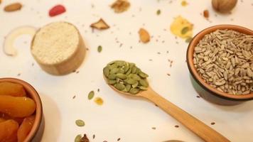 Healthy vegetarian food concept. Assortment of dried fruits, nuts and seeds on white background. Top view. video