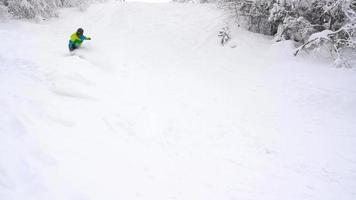 View from height to man is riding a snowboard on a snow-covered field on a cable behind a car video