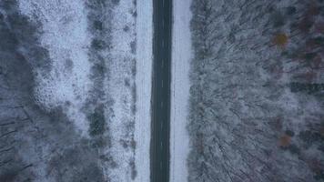 Aerial view on car driving through winter forest road. Scenic winter landscape video