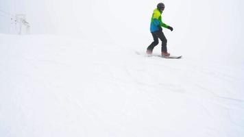 Visão a partir de altura para homem é equitação uma snowboard em uma coberto de neve campo em uma cabo atrás uma carro video