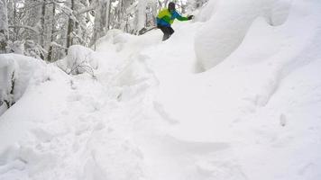 View from height to man is riding a snowboard on a snow-covered field on a cable behind a car video