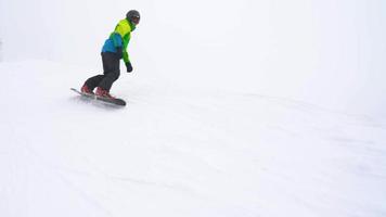 Visão a partir de altura para homem é equitação uma snowboard em uma coberto de neve campo em uma cabo atrás uma carro video