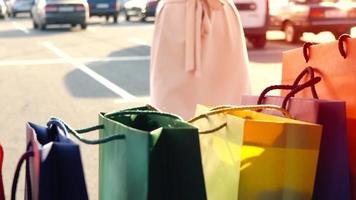 bellissimo ragazza scelte su shopping borse a partire dal il tronco di il macchina, si chiude esso e le foglie. lento movimento video