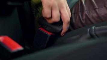 Female hand fastening car safety seat belt while sitting inside of vehicle before driving video