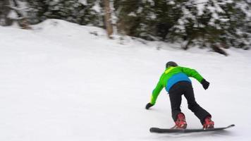 Visão a partir de altura para homem é equitação uma snowboard em uma coberto de neve campo em uma cabo atrás uma carro video